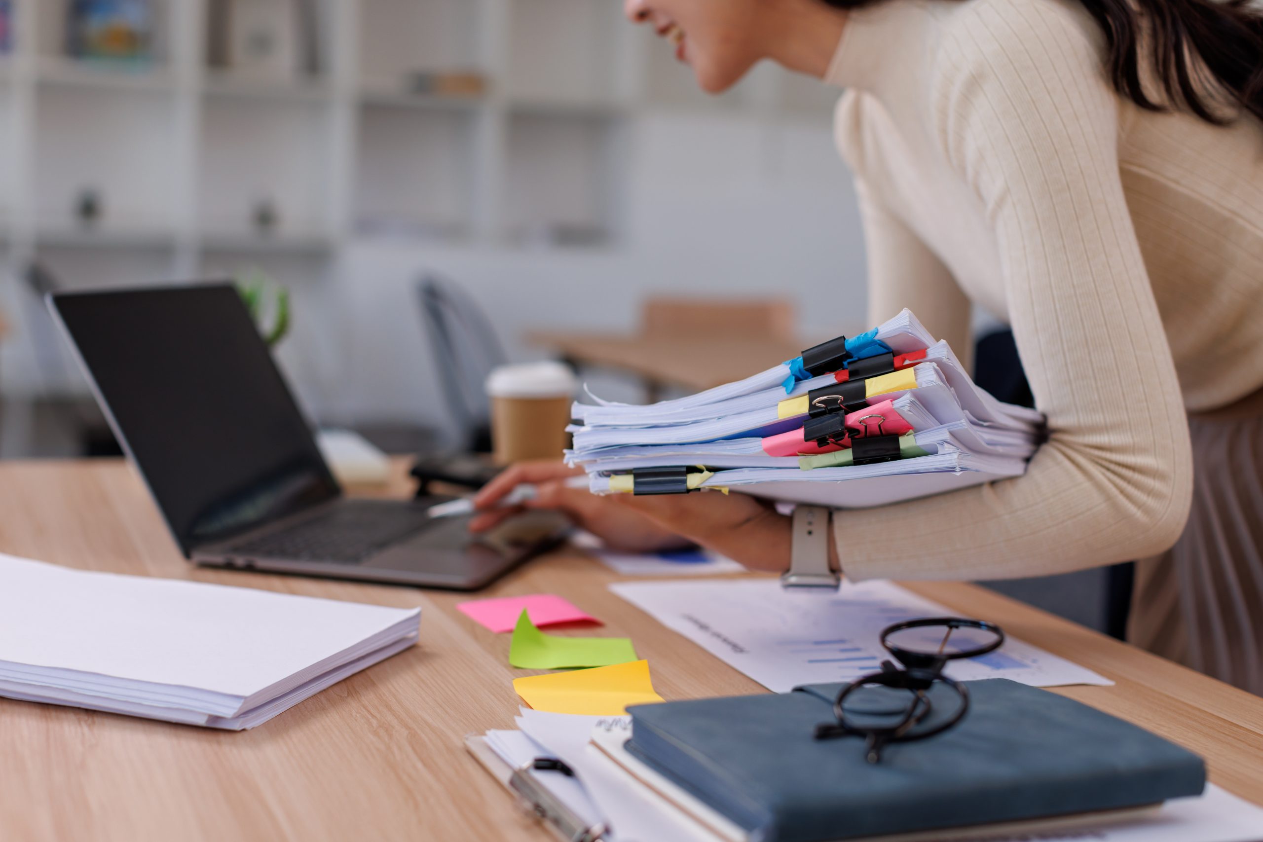Business Documents, woman hands working in Stacks of paper files for searching and checking unfinished document achieves on folders papers